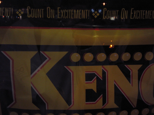A Keno poster that proclaims to 'count on excitement' above the Keno logo. Quite a dark photo and out of focus.