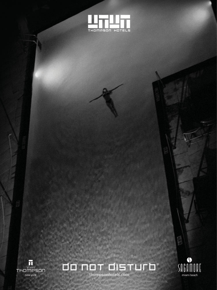 A black and white image of a person lying in a large L shaped pool. A bit creepy vibe.