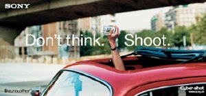 An image of a red car with a hand coming out of its skylight, taking a photo with a hand help small camera.